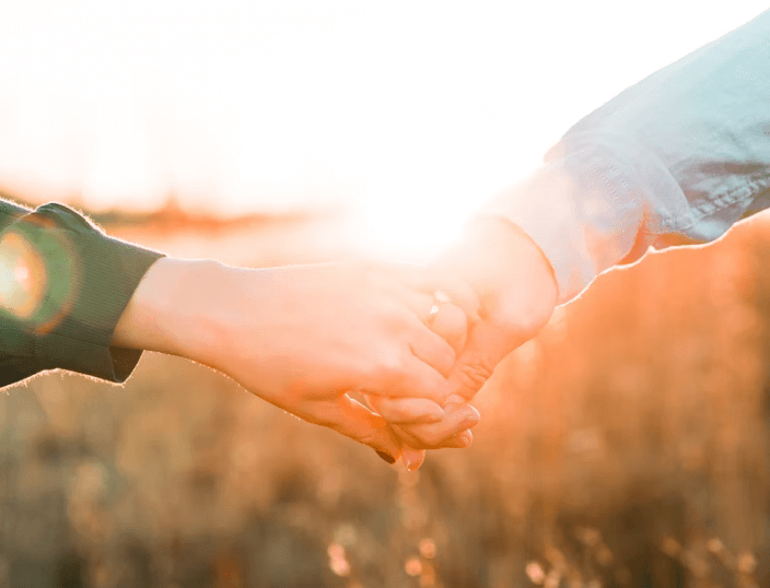Young couple holding hand outdoor during sunrise